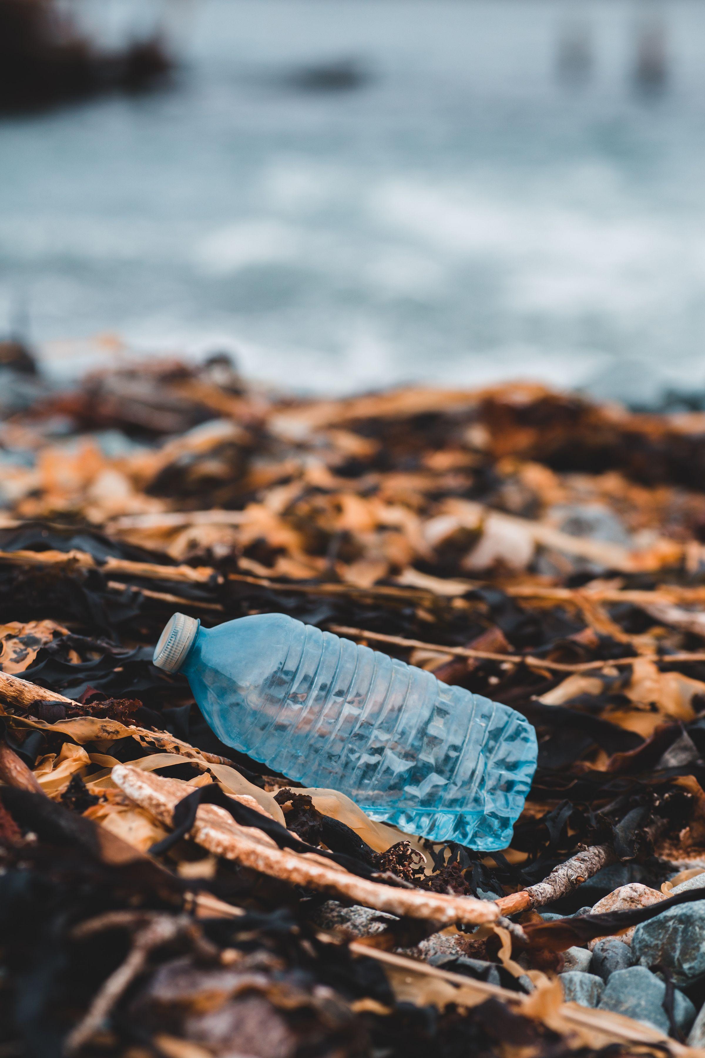 picture of a bluish plastic bottle with the ocean as background